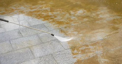 Reiniging van een betonnen oppervlak met een hogedrukspuit waarbij oxaalzuur wordt gebruikt om roestvlekken te verwijderen.