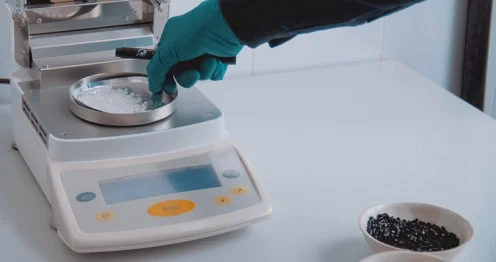 Persoon in laboratorium die een chemische stof afweegt op een digitale weegschaal voor het berekenen van de molariteit.