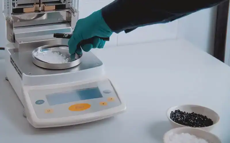 Persoon in laboratorium die een chemische stof afweegt op een digitale weegschaal voor het berekenen van de molariteit.