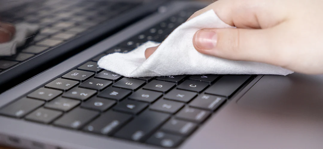 Afbeelding van iemand die zijn laptop schoonmaakt met een doekje