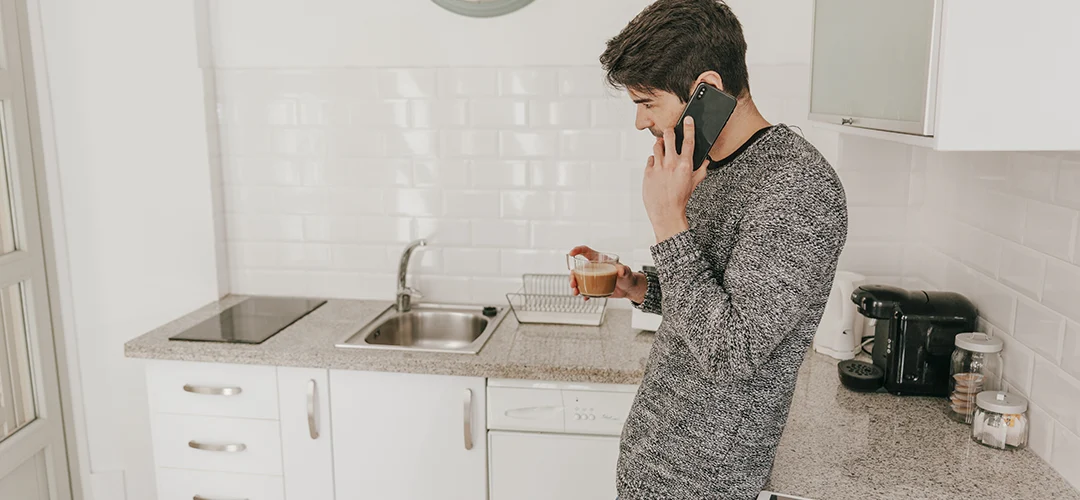 Ein Mann ruft in seiner Küche einen Klempner, weil das Spülbecken verstopft ist.