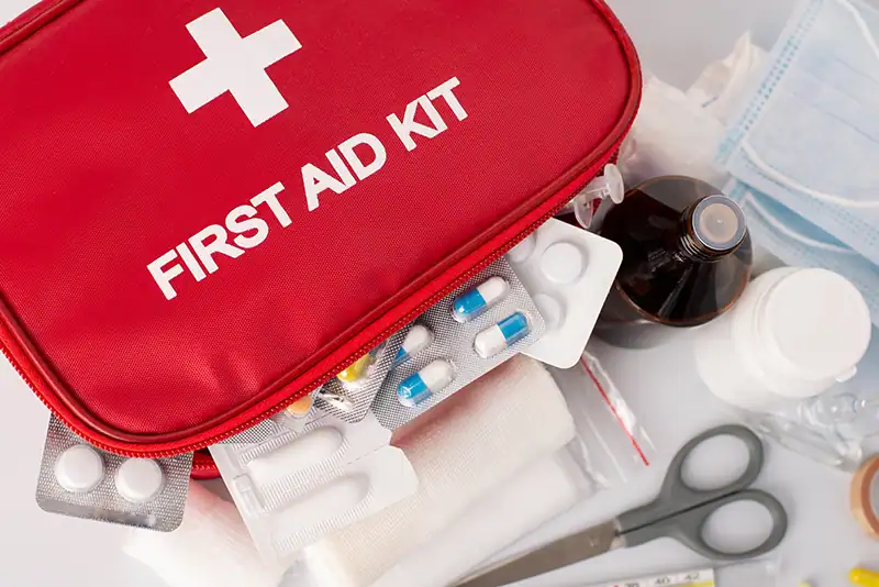 Geöffneter Erste-Hilfe-Kasten mit ordentlich angeordneten Pflastern, Verbänden, Schere, Handschuhen und antiseptischen Tüchern.