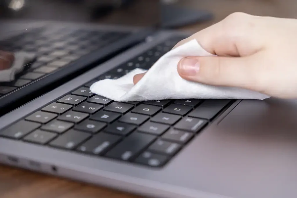 Bild einer Person, die ihren Laptop mit einem Tuch reinigt
