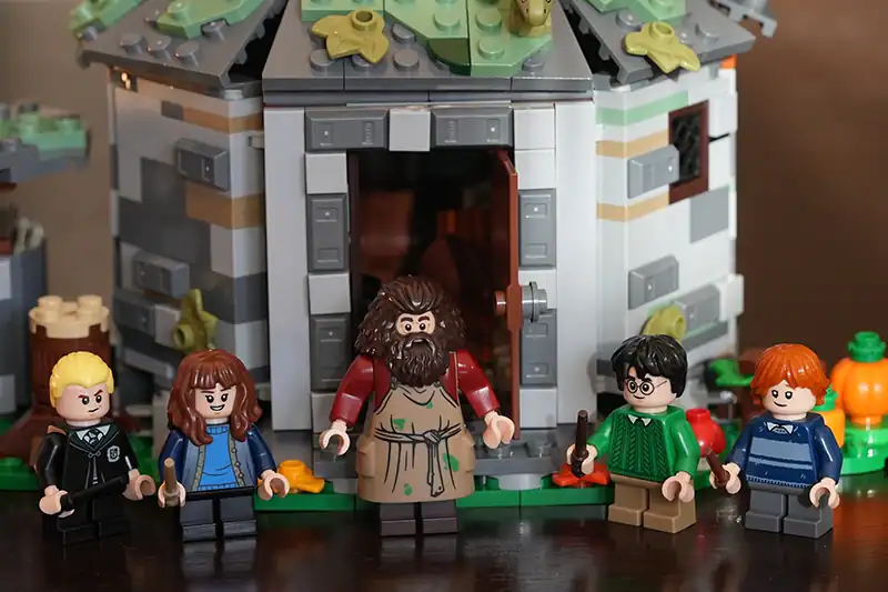 Lego-Figuren aus Harry Potter stehen vor einem detaillierten Lego-Modell eines Häuschens.